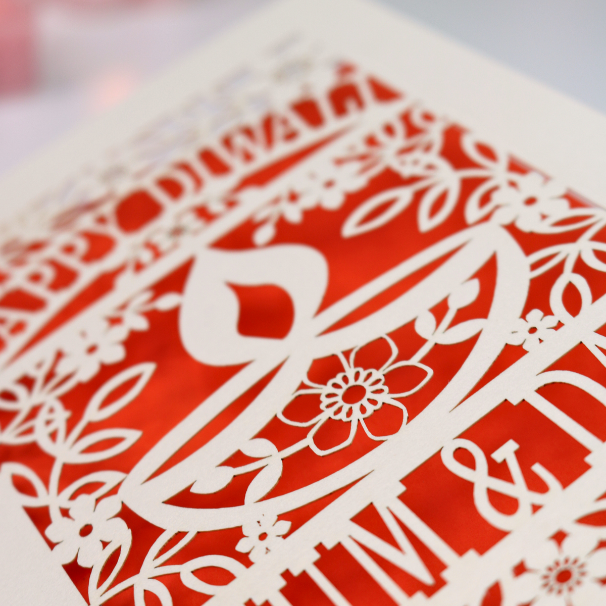 A close-up of a cream laser-cut paper Diwali greeting card or art print, featuring festive patterns, a diya, and decorative text.