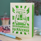 Laser-cut Driving Test Congratulations card with 'You Passed! Congratulations Frankie' text on a wooden surface with a pen.