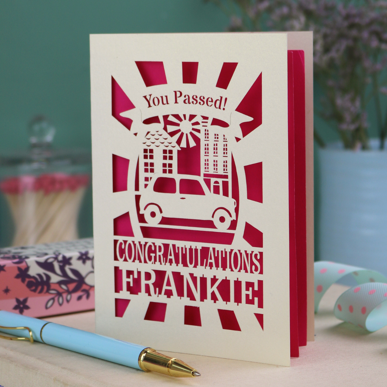 Laser-cut Driving Test Congratulations card with 'You Passed! Congratulations Frankie' text on a wooden surface with a pen.