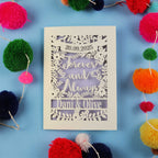 Decorative engagement card with personalized text on a blue background with colourful pom-poms.