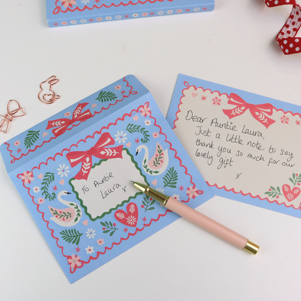 Decorative notecard with swan design, pen, and gift box on a white background