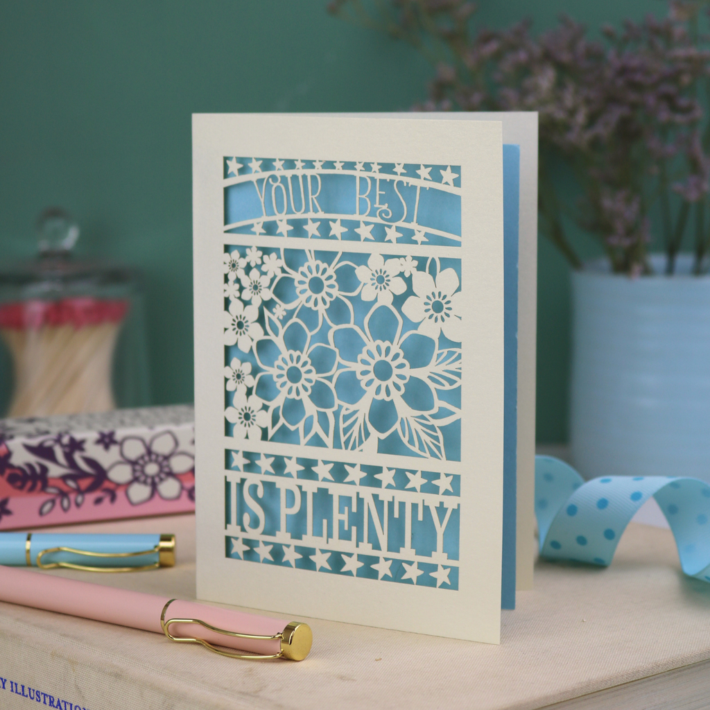 Decorative laser cut greetings card with floral design and text, 'Your best is plenty' on a table with stationery items.