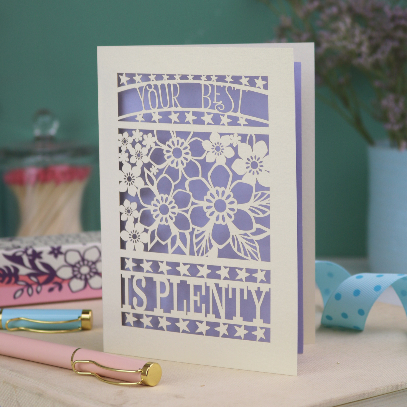 Decorative laser cut greetings card with floral design and text, 'Your best is plenty' on a table with stationery items.