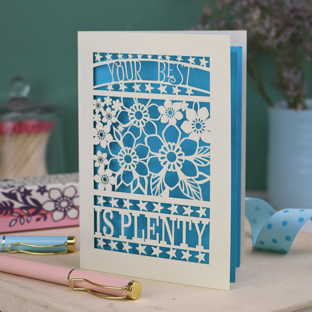 Decorative laser cut greetings card with floral design and text, 'Your best is plenty' on a table with stationery items.