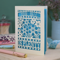 Decorative laser cut greetings card with floral design and text, 'Your best is plenty' on a table with stationery items.
