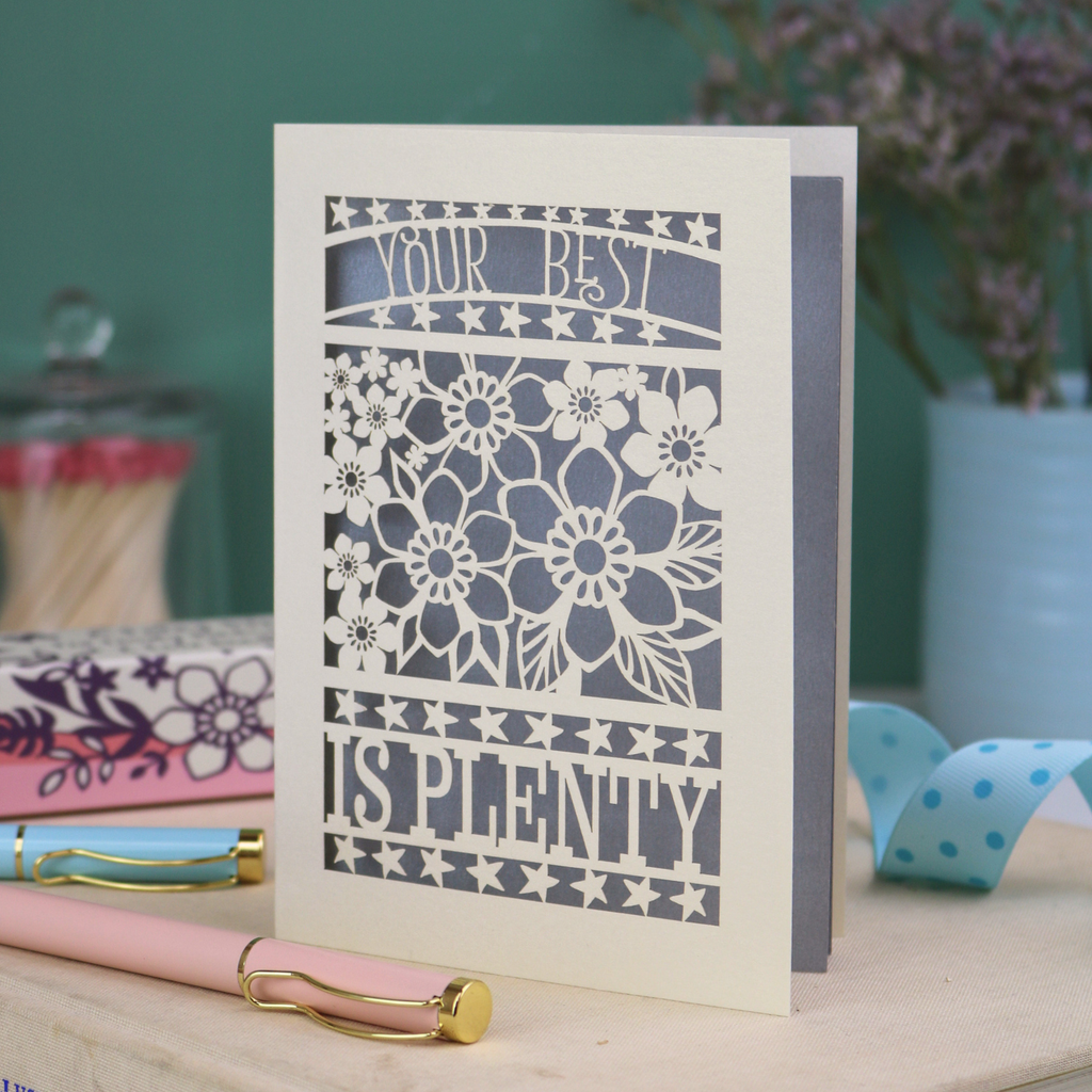 Decorative laser cut greetings card with floral design and text, 'Your best is plenty' on a table with stationery items.