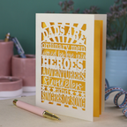 A laser cut father's Day card with cut out quote, "Dads are ordinary men turned by love into heroes, adventurers, storytellers and singers of song", with a cream card and bright yellow paper insert