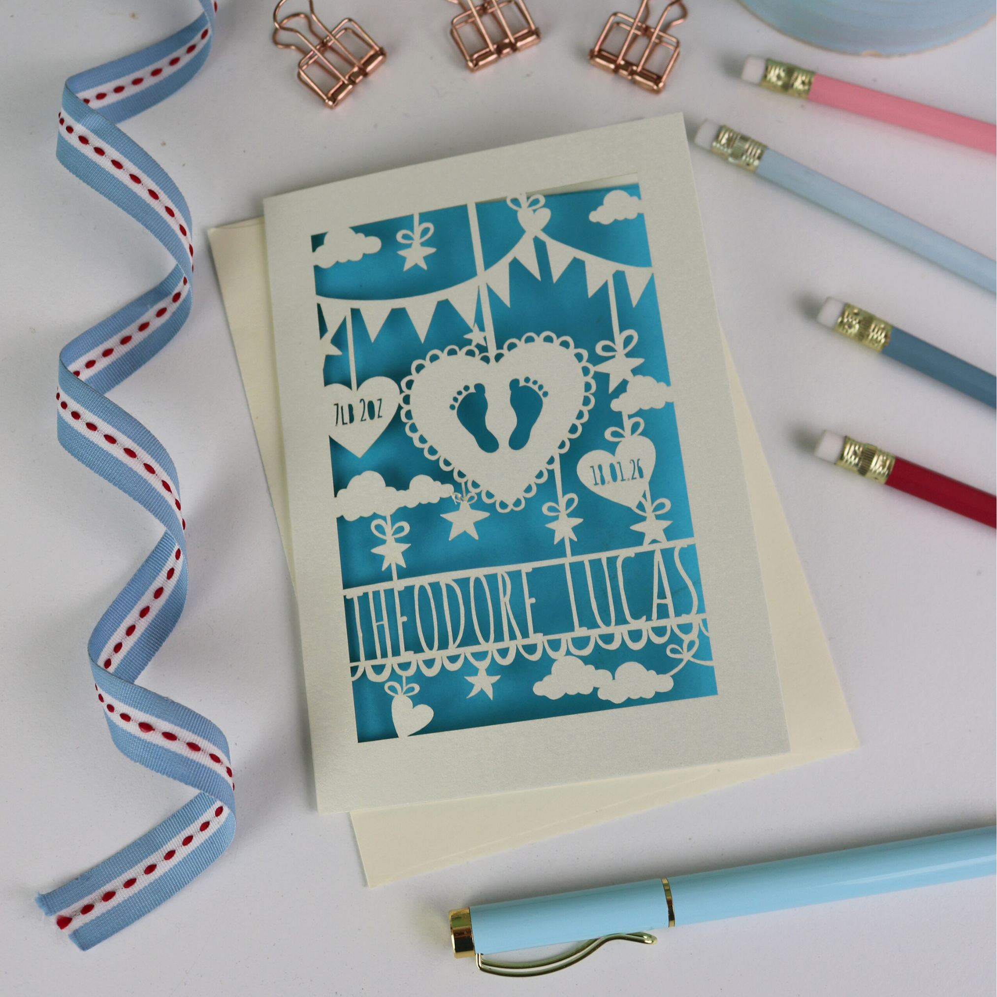 New Baby Card with decorative elements on a white surface with stationery items.