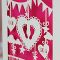 Decorative baby card with cut-out designs on a pink background