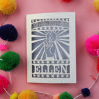 A paper cut good luck card personalised with a name and featuring a cut out hand with crossed fingers, surrounded by sunbeams