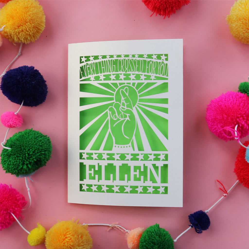 A personalised laser cut good luck card that shows a cut out hand with fingers crossed and the words "Everything crossed for you"