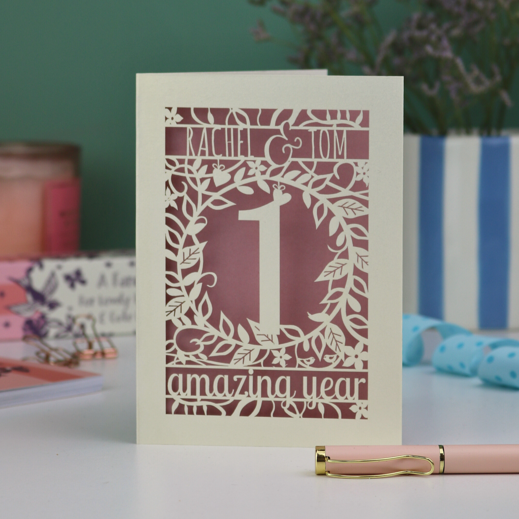 First wedding anniversary Card with '1 amazing year' design on a table with a pen and decorative items.