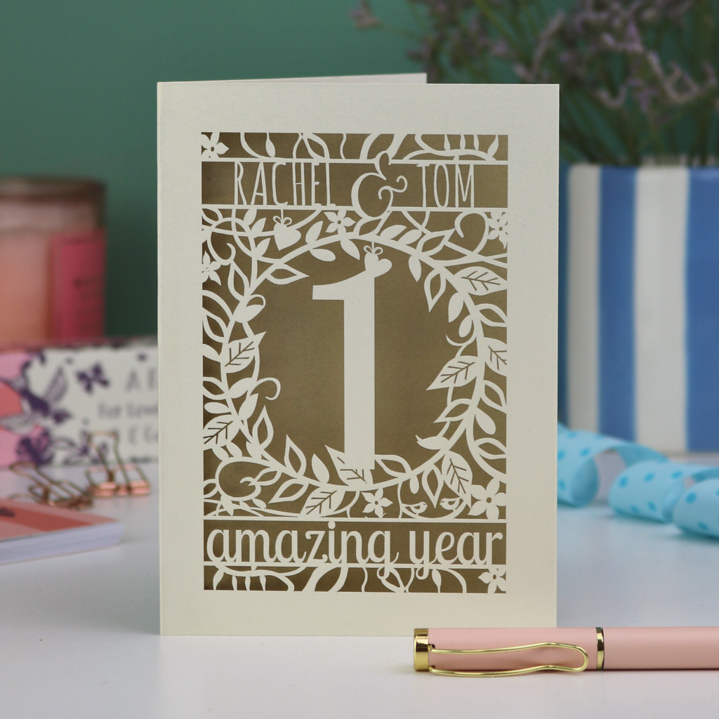 Paper anniversary Card with '1 amazing year' design on a table with a pen and decorative items.