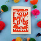 First Birthday card with colourful pom-poms on a blue background