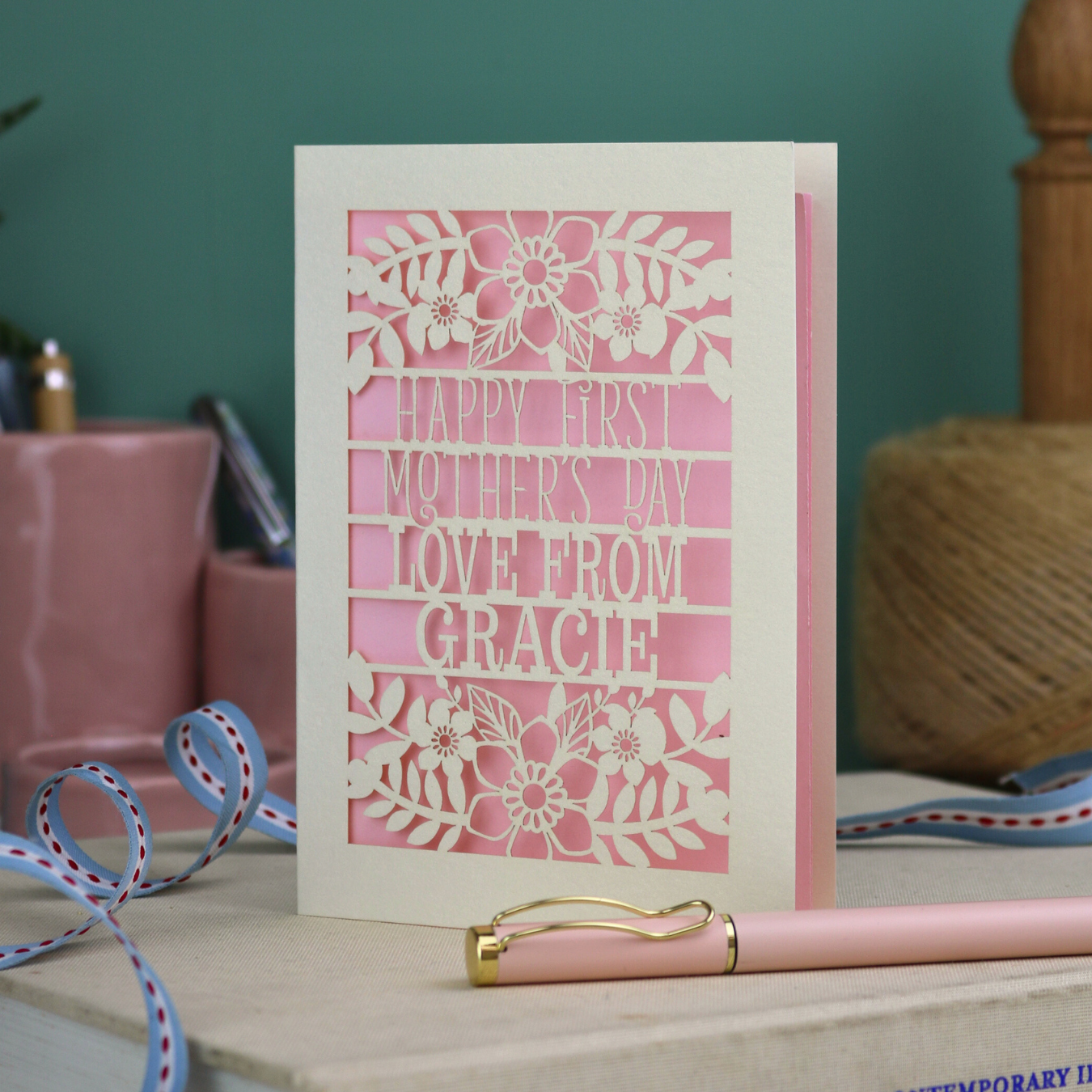A floral laser cut 1st mother's day card with cut out text, "Happy First Mother's Day Love From" and is personalised with a name. 