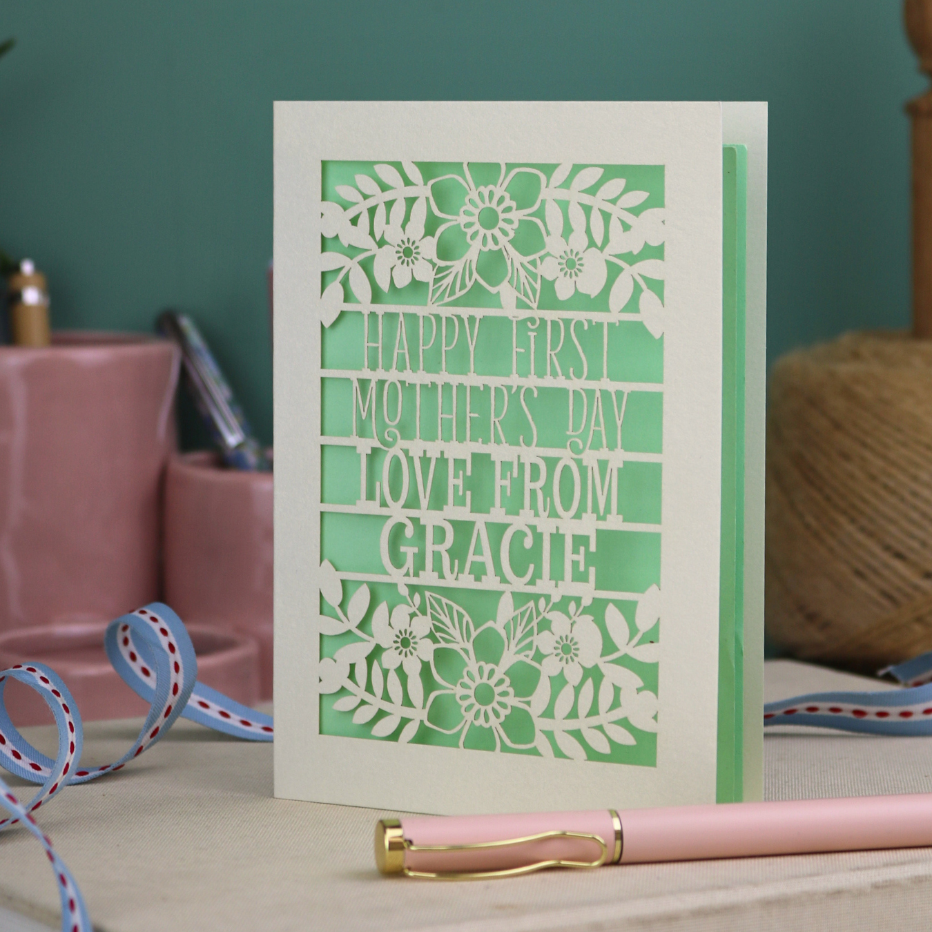A floral laser cut 1st mother's day card with cut out text, "Happy First Mother's Day Love From" and is personalised with a name. 