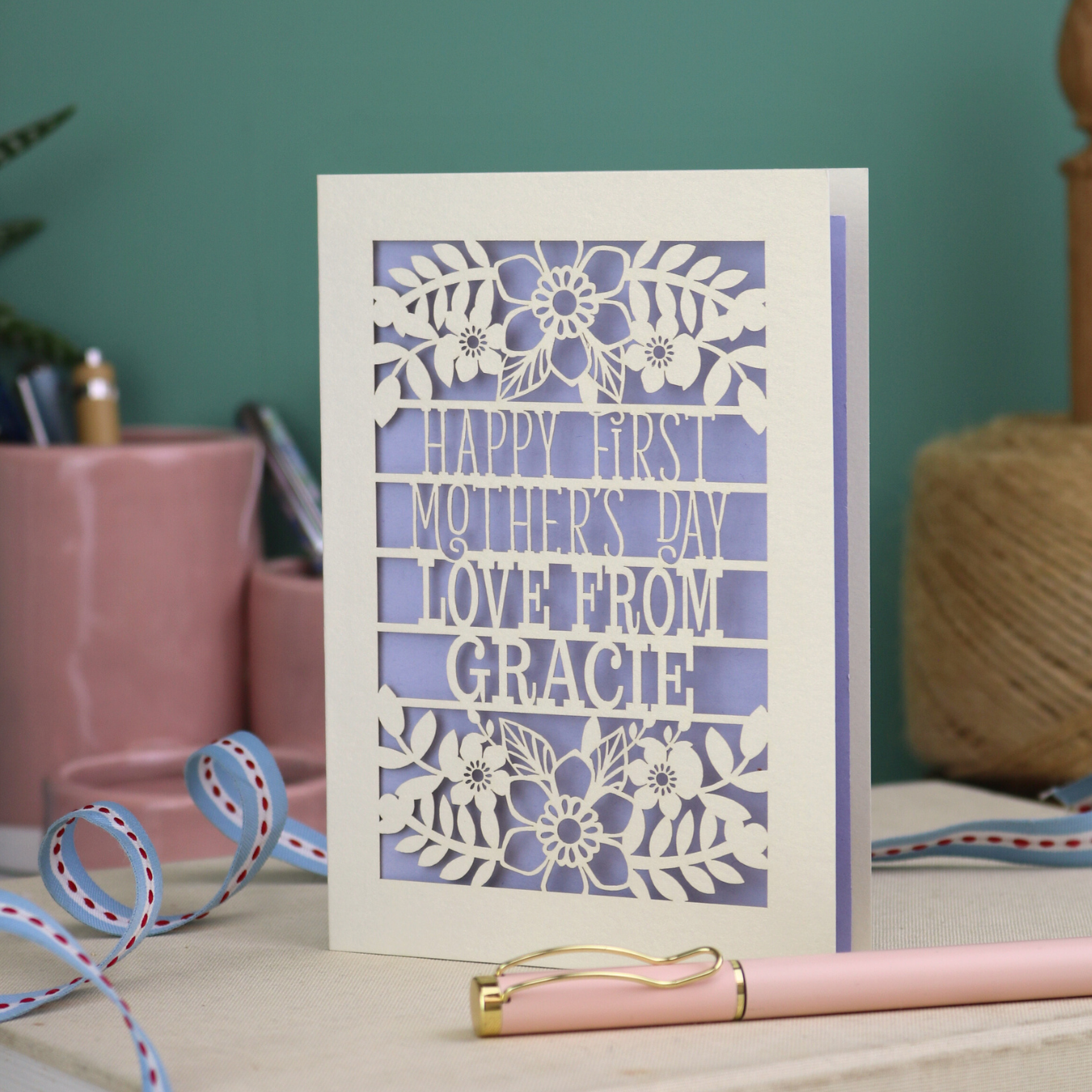 A floral laser cut 1st mother's day card with cut out text, "Happy First Mother's Day Love From" and is personalised with a name. 