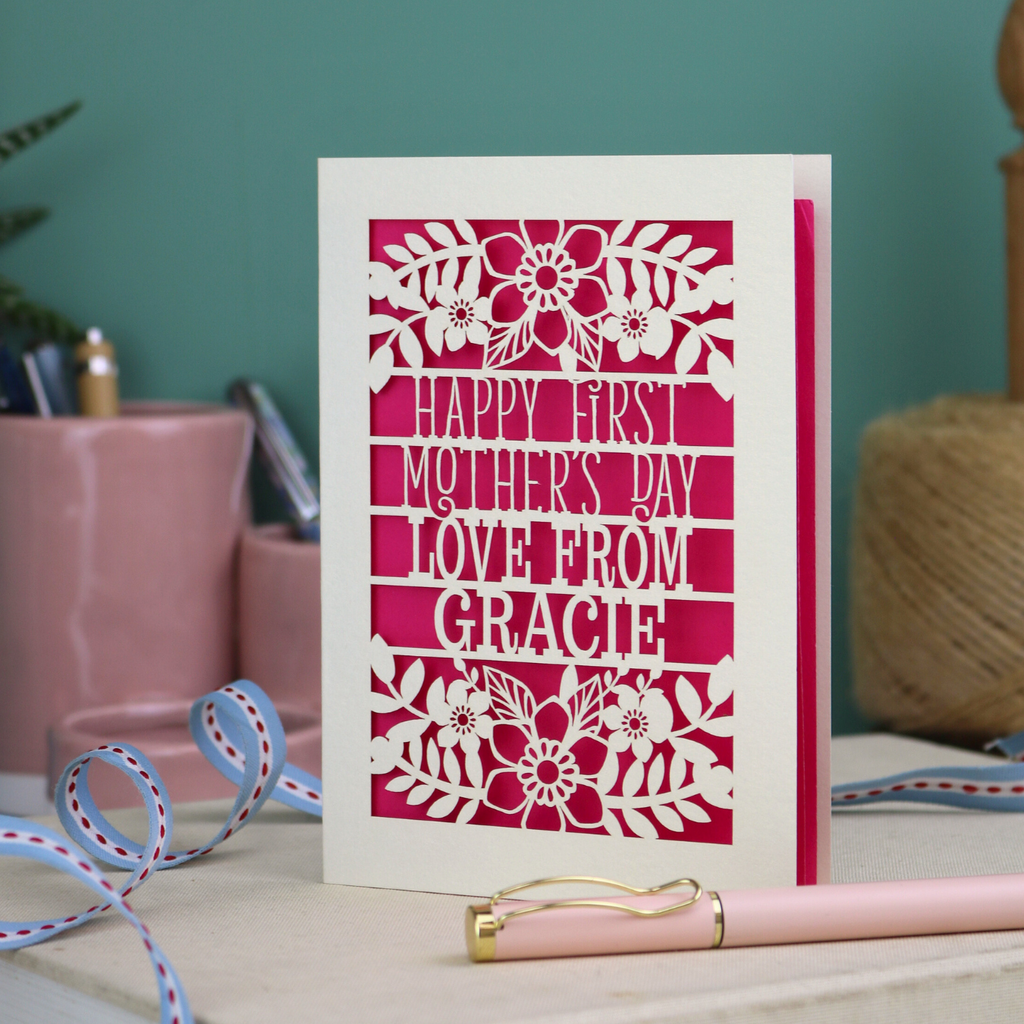 A floral laser cut 1st mother's day card with cut out text, "Happy First Mother's Day Love From" and is personalised with a name. 
