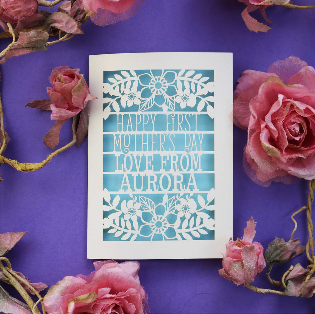 A laser cut First Mother's Day card with cut out text that says "Happy First Mother's Day, love from" and is personalised with a name