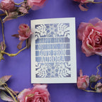 A laser cut First Mothers Day card with cut out text that says "Happy First Mother's Day, love from" and is personalised with a name