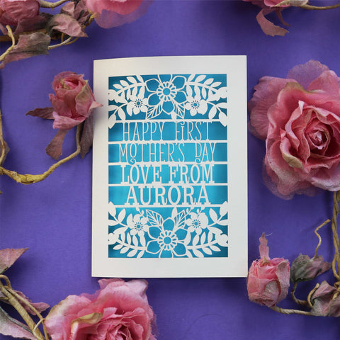 A laser cut First Mother's Day card with cut out text that says "Happy First Mother's Day, love from" and is personalised with a name
