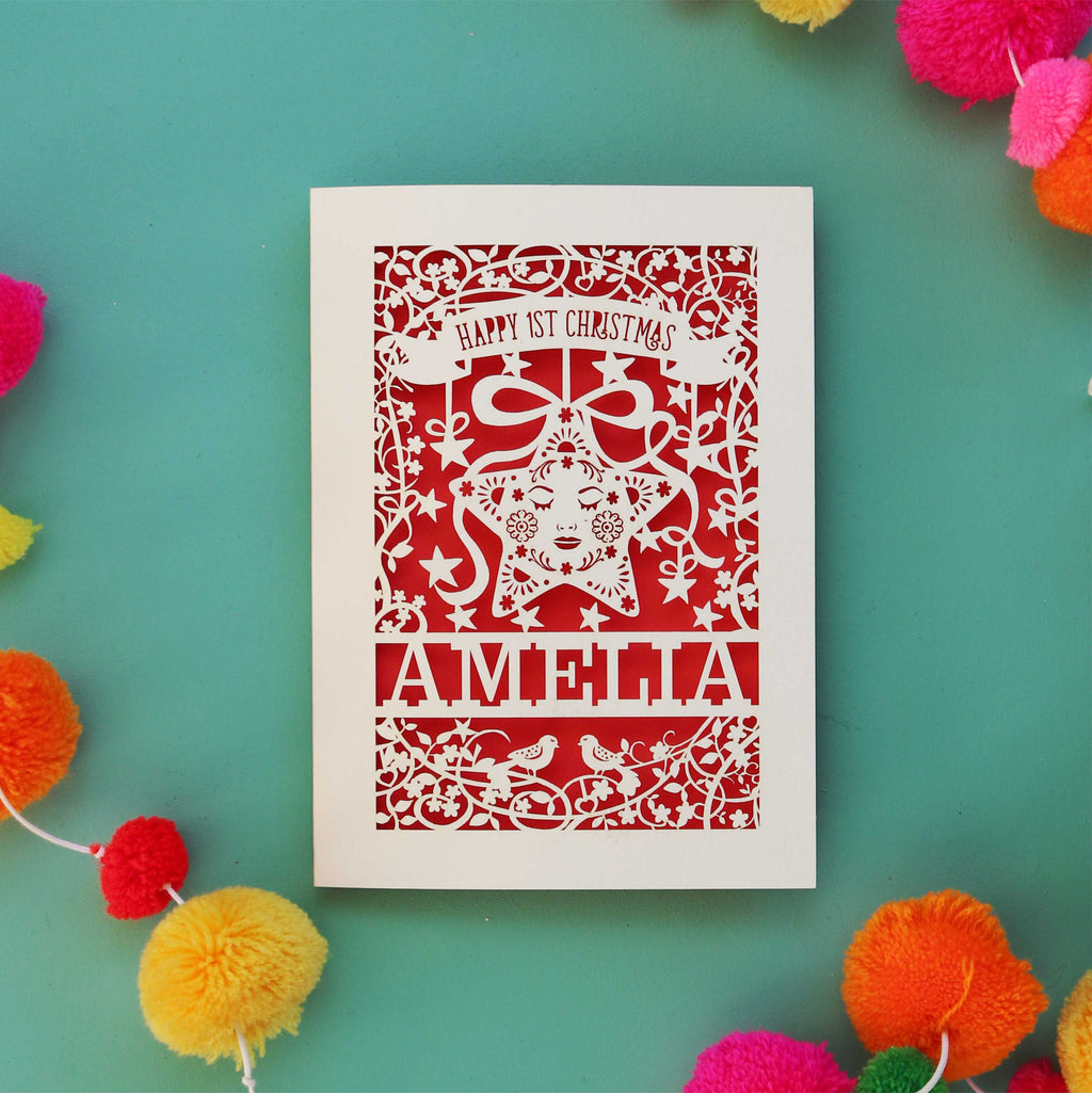 A personalised laser cut card for baby's first Christmas. A star is inside a border of laser cut leaves