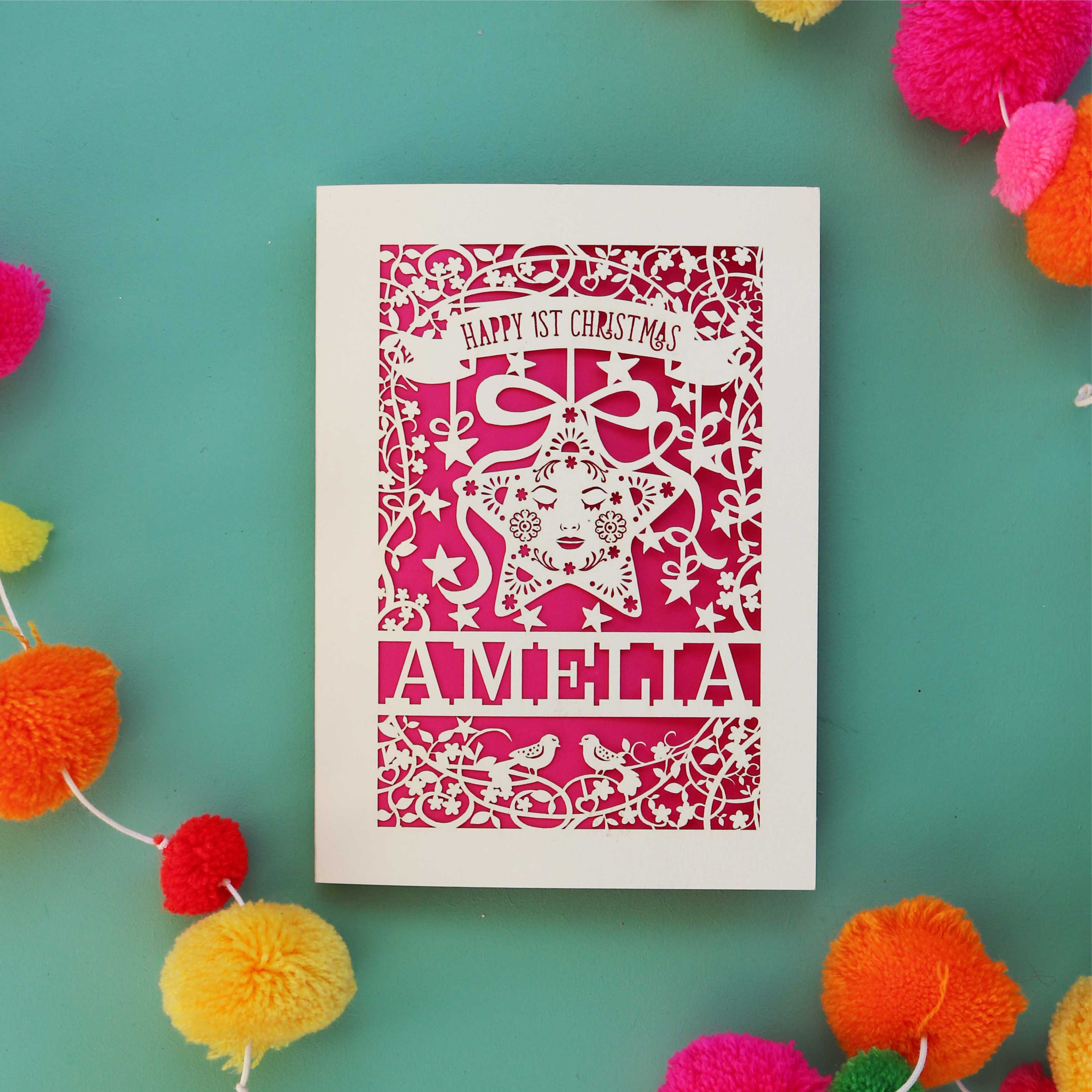 A laser cut Christmas card for baby's first Christmas. A star is inside a floral border with baby's name at the bottom.