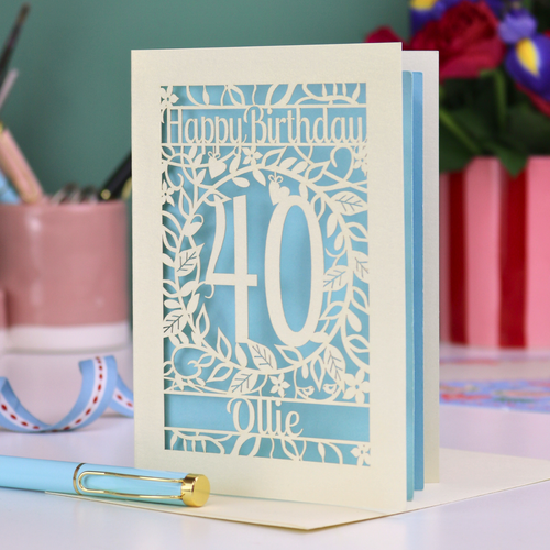 Personalised Birthday card with 'Happy Birthday 40 Ollie' on a desk with stationery items.