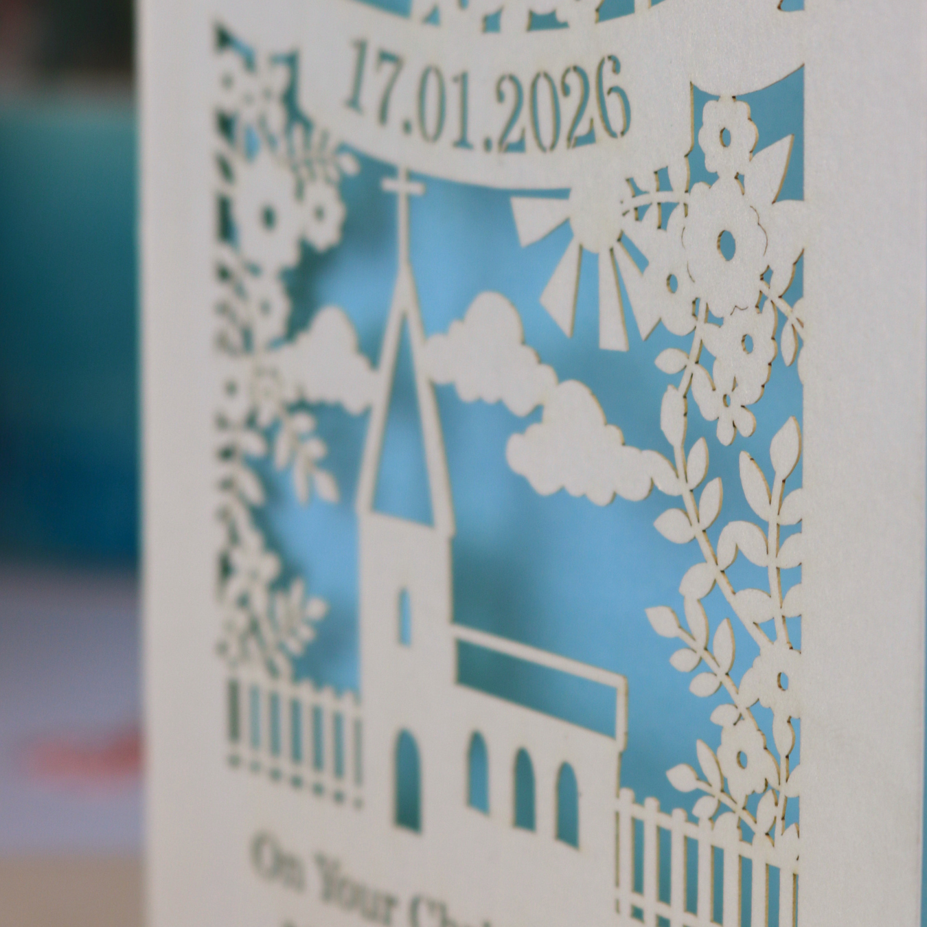 A laser cut floral Christening card with cut out church design and the date in a stencil font in a banner, with "On Your Christening Day" and the name "Maggie Jayne Chilton" underneath.