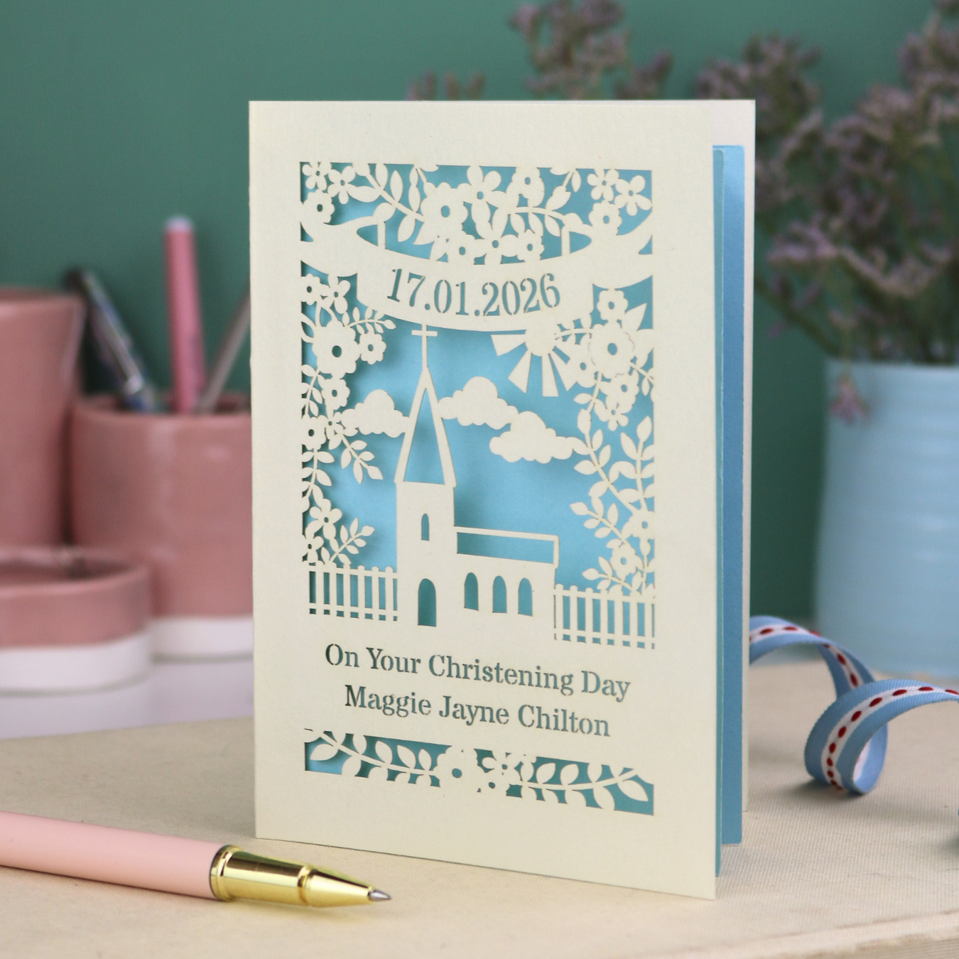A laser cut floral Christening card with cut out church design and the date in a stencil font in a banner, with "On Your Christening Day" and the name "Maggie Jayne Chilton" underneath.