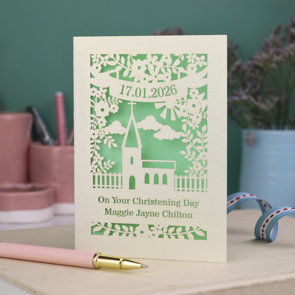 A laser cut floral Christening card with cut out church design and the date in a stencil font in a banner, with "On Your Christening Day" and the name "Maggie Jayne Chilton" underneath.