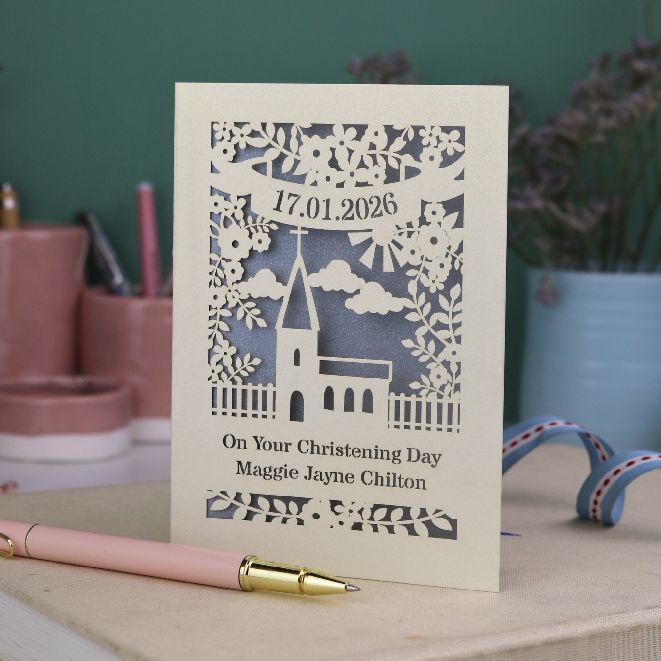 A laser cut floral Christening card with cut out church design and the date in a stencil font in a banner, with "On Your Christening Day" and the name "Maggie Jayne Chilton" underneath.