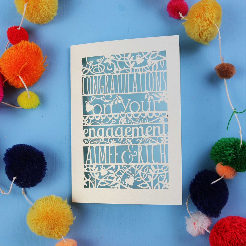 Personalised engagement Card with 'Congratulations on your engagement' text on a blue background with colourful pom-poms.