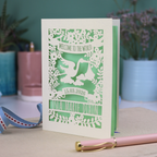 A personalised new baby card with laser cut floral stork design and "Welcome to the World" in cut out text in a banner, with the baby's date of birth and name