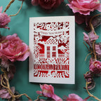 A personalised new home card, laser cut and featuring a house surrounded by flowers. There is a banner with the words "Happy new home" and a line of text at the bottom of the card