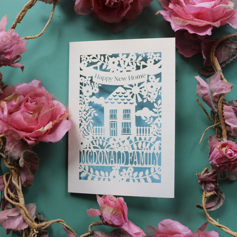 A laser cut house card for new homes. Card says "Happy new home" and is personalised with the recipient/s' name in a line of text - A6 / Light Blue