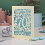 A personalised 70th birthday card, laser cut with floral design and 'Happy Birthday', with a name at the bottom and a big number 70 in the centre. 