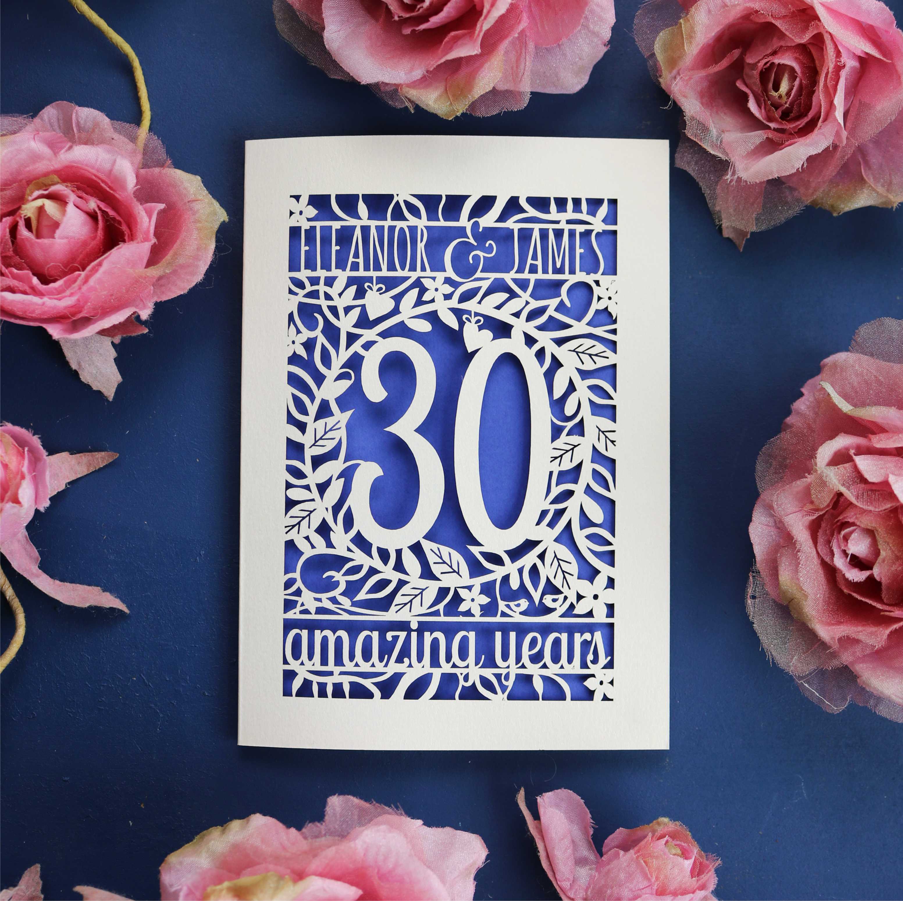 A cream and violet laser cut card for a 30th anniversary. Card is personalised with text and has intricate floral details in the border. 