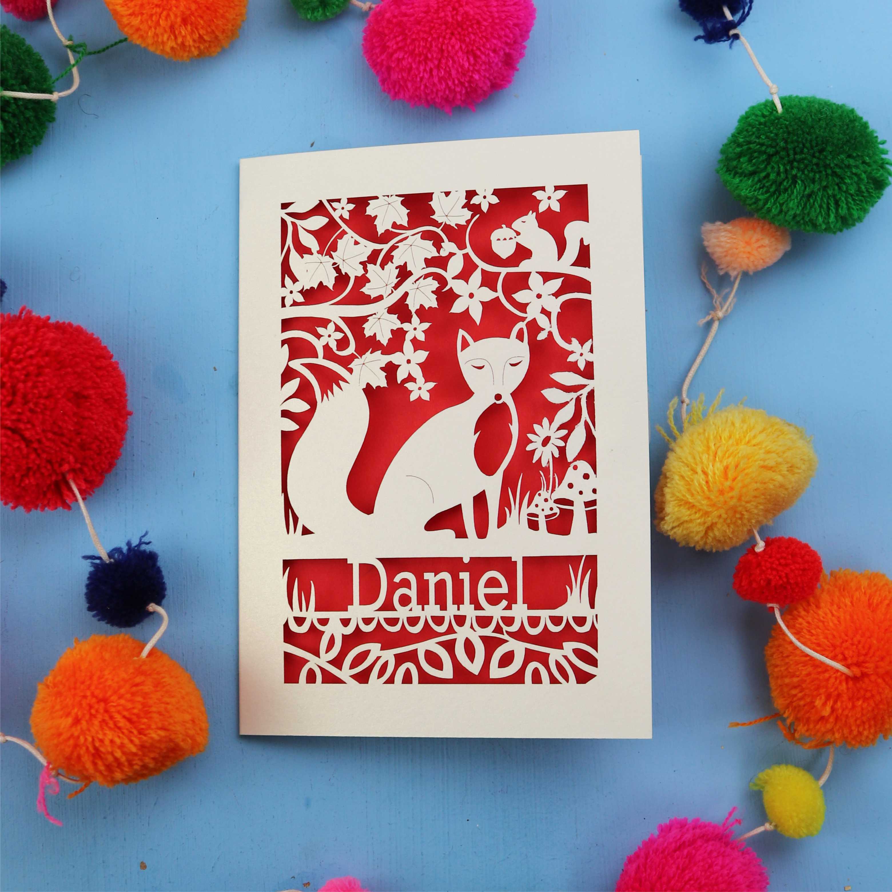 Decorative fox birthday card with fox design and colourful pom-poms on a blue background
