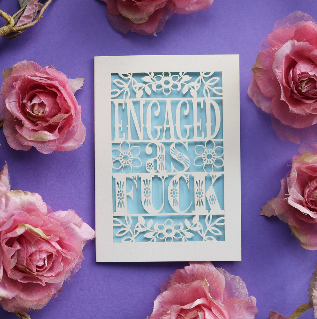 A cream and light blue cut out engagement card that says "Engaged as fuck"