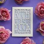 The Words "Engaged as fuck" laser cut from cream card.
