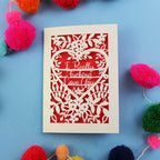 laser cut funny Valentine's Card with floral design and text on a blue background with colourful pom-poms
