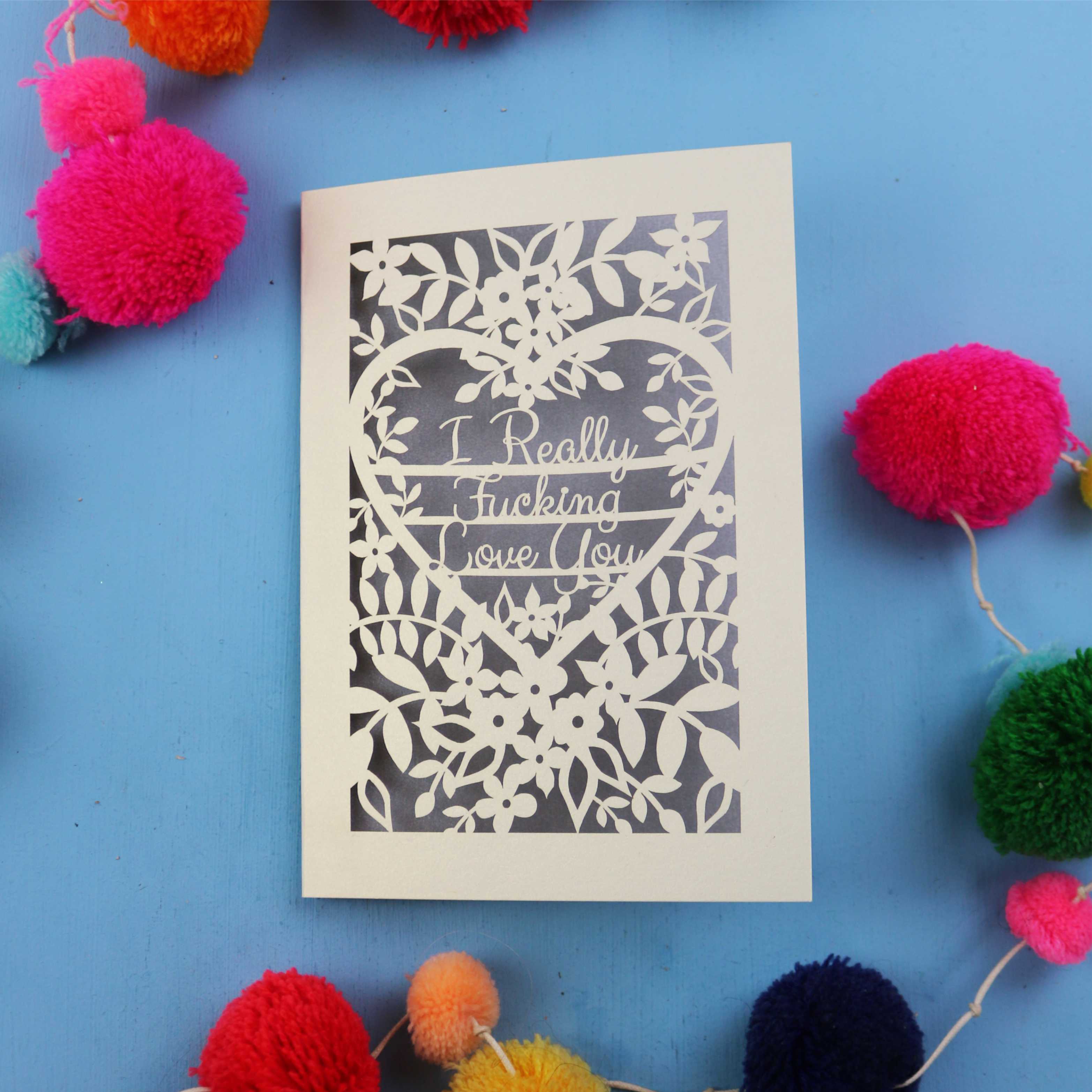 Funny Valentine's Card with floral design and text on a blue background with colourful pom-poms