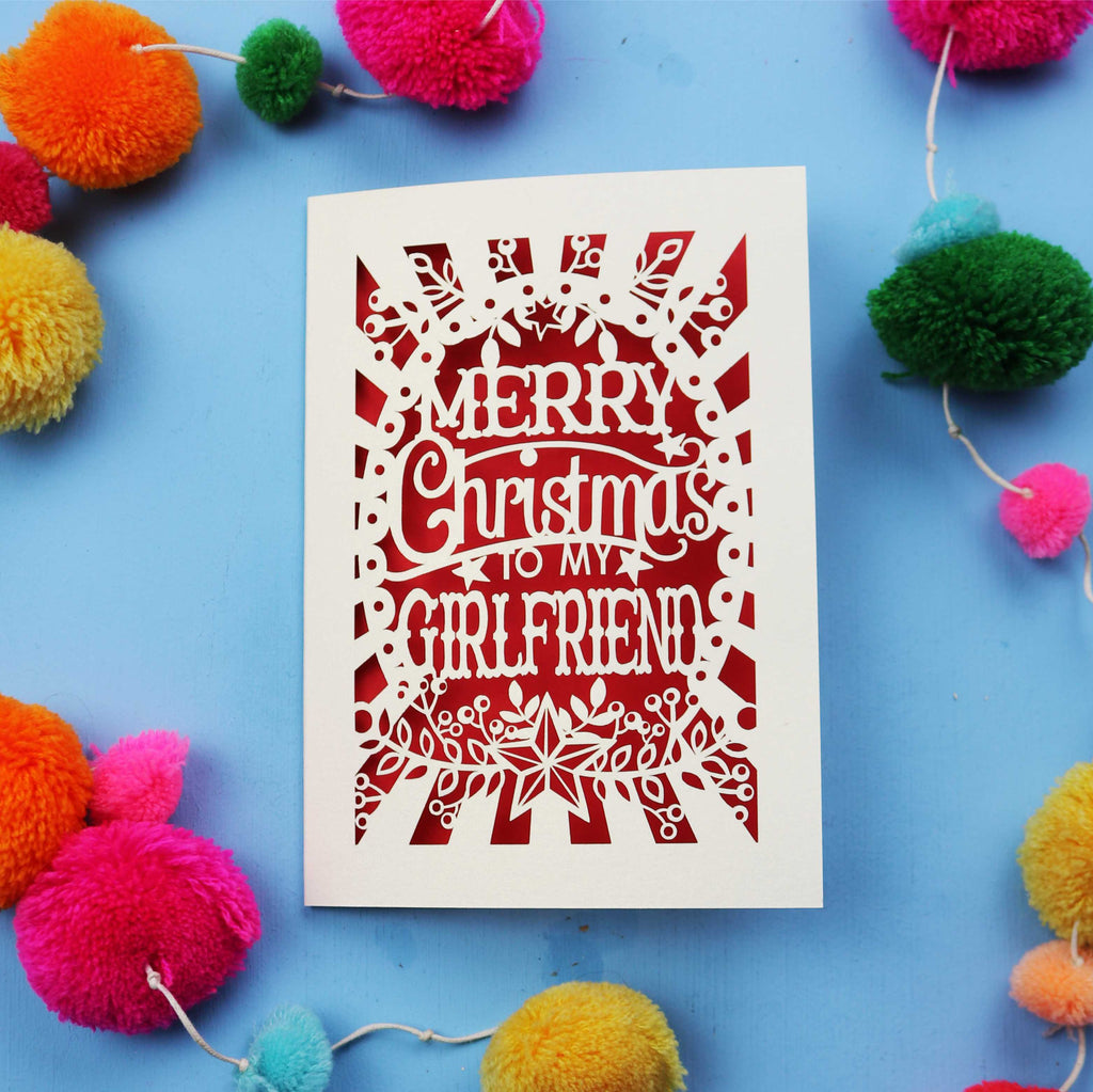 Christmas card with 'Merry Christmas to my girlfriend' text on a blue background with colourful pom-poms.