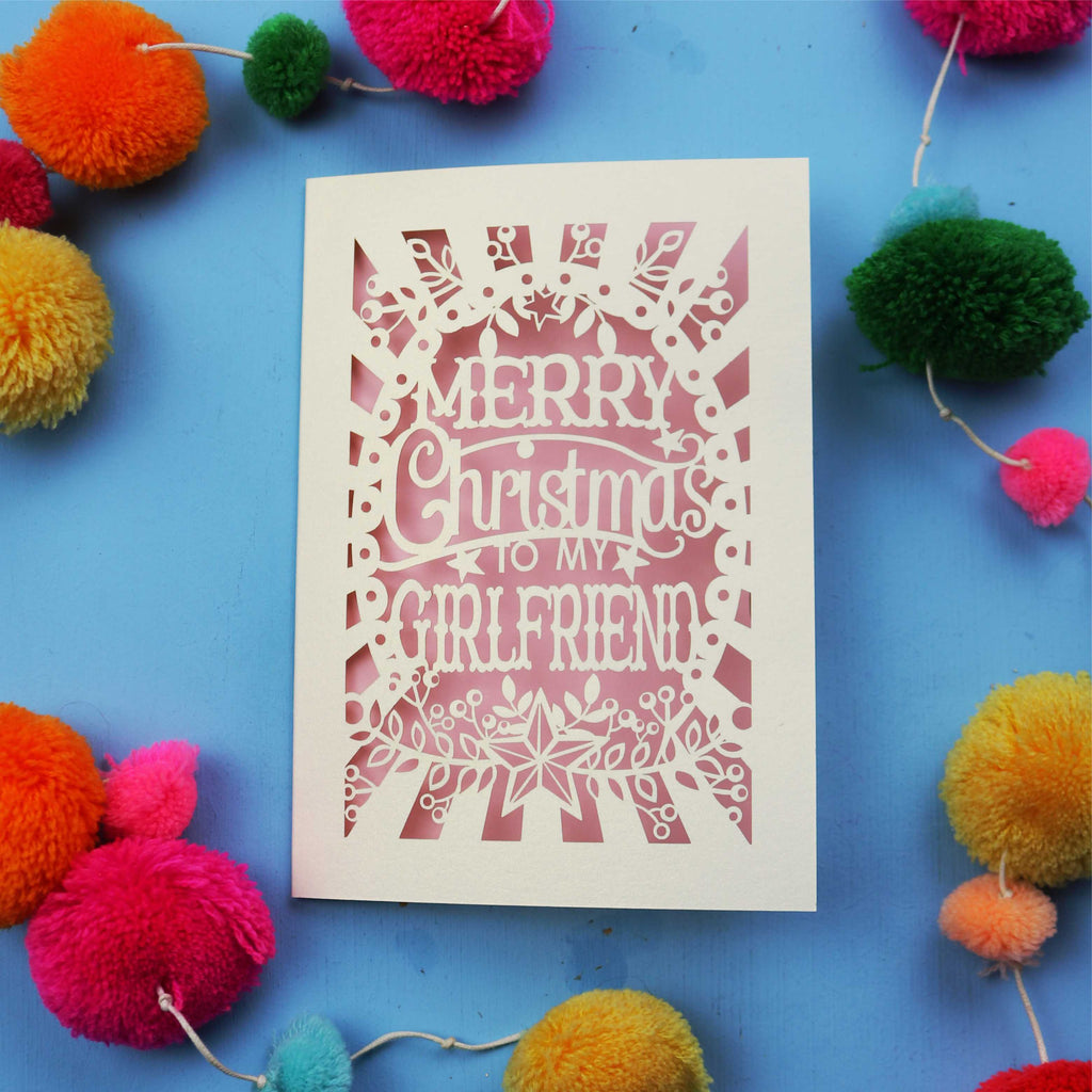 Christmas card with 'Merry Christmas to my girlfriend' text on a blue background with colourful pom-poms.