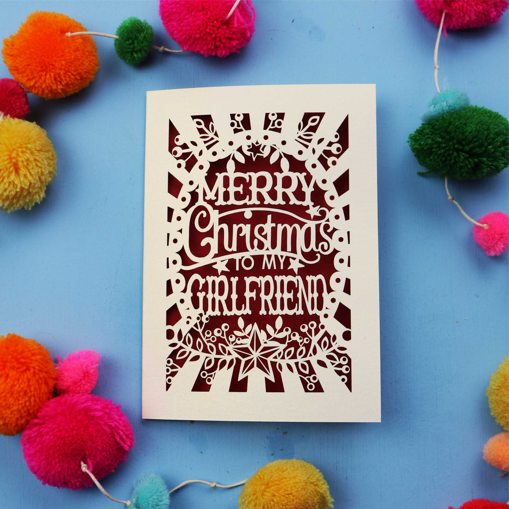 Christmas card with 'Merry Christmas to my girlfriend' text on a blue background with colourful pom-poms.