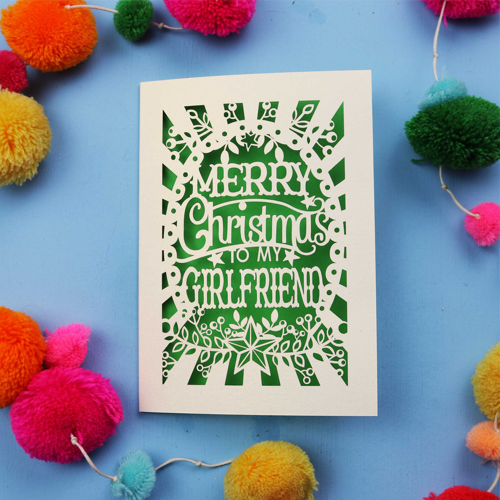 Christmas card with 'Merry Christmas to my girlfriend' text on a blue background with colourful pom-poms.