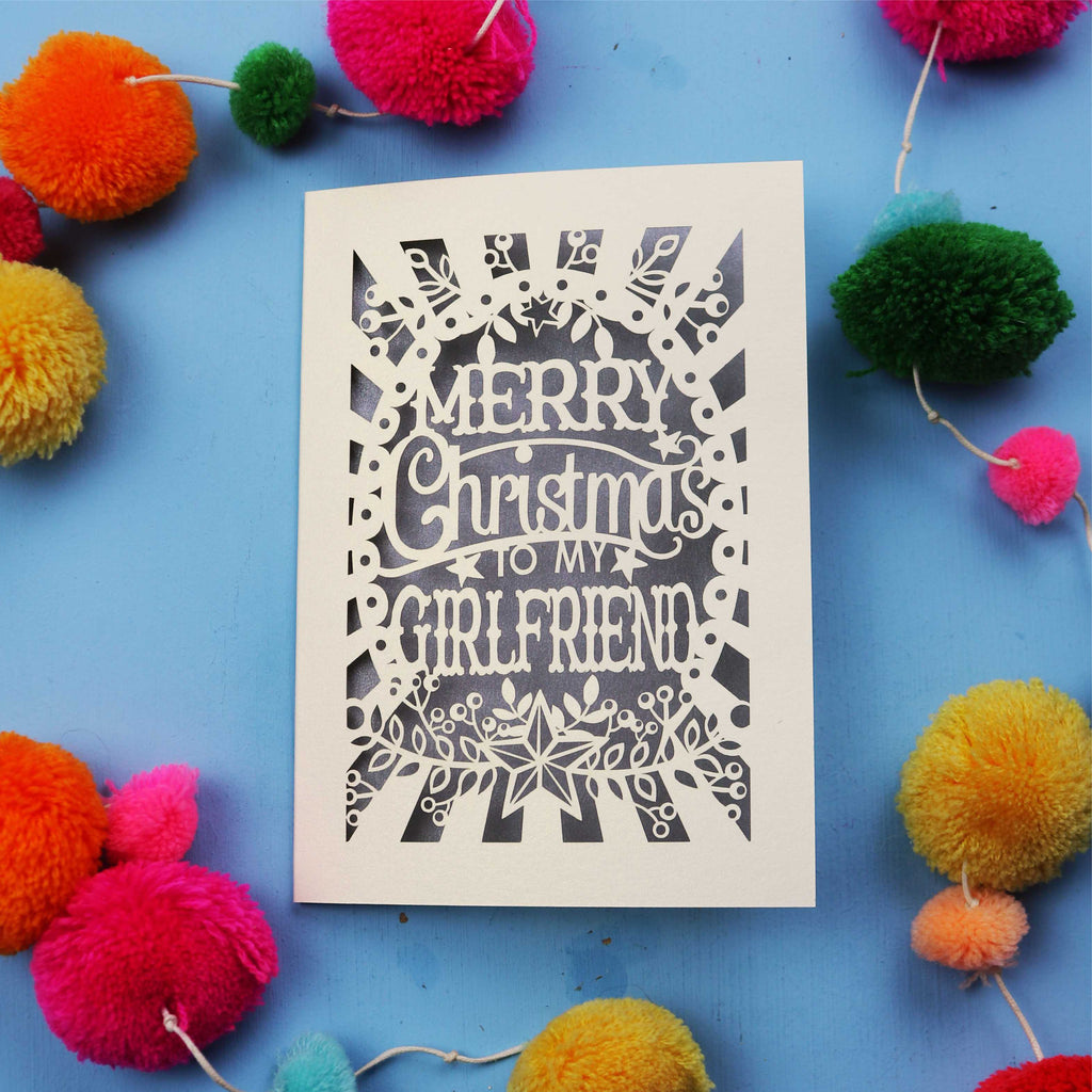 Christmas card with 'Merry Christmas to my girlfriend' text on a blue background with colourful pom-poms.