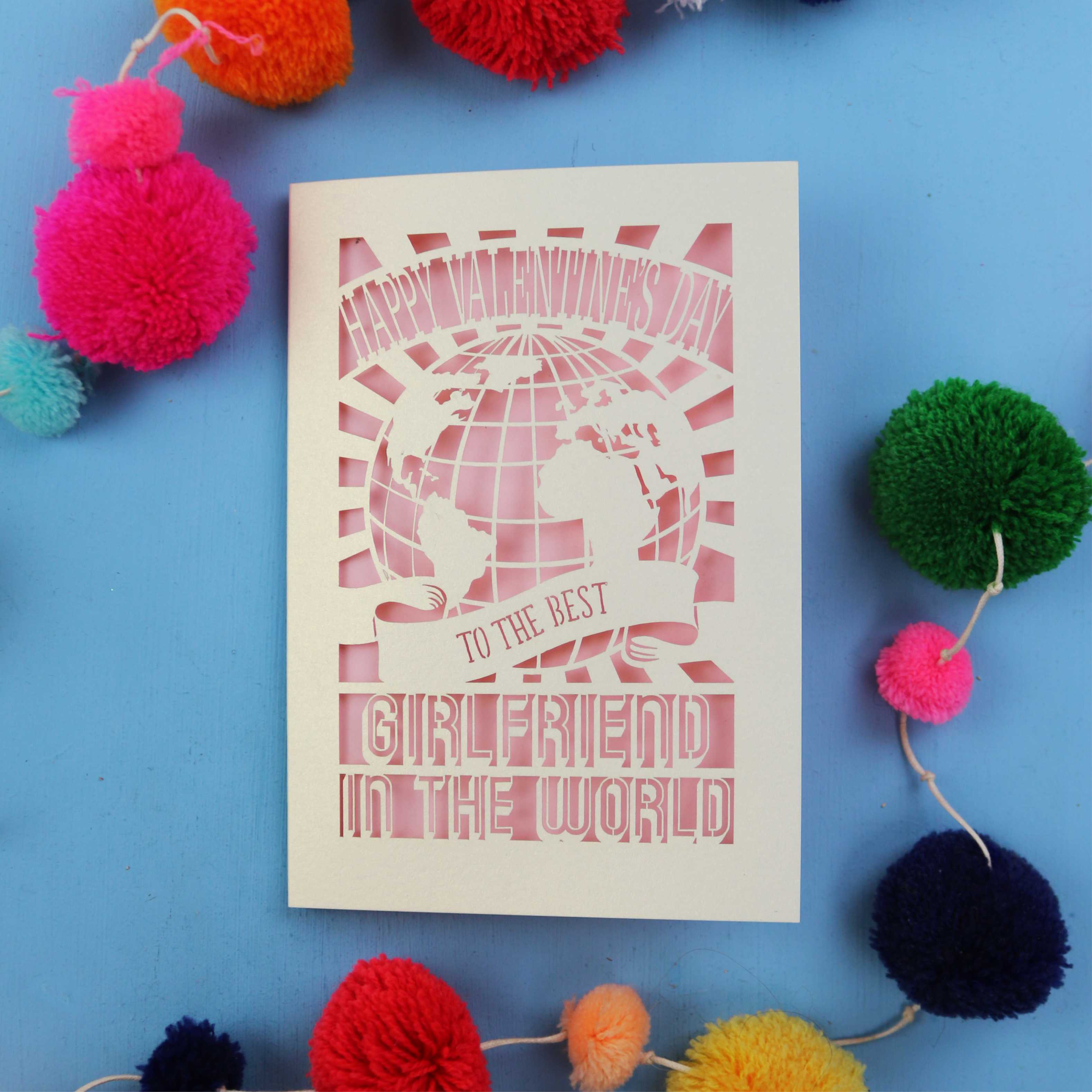 A laser cut girlfriend Valentine's card that features a paper cut out World design and the words "Happy Valentine's Day to the Best Girlfriend in the World"