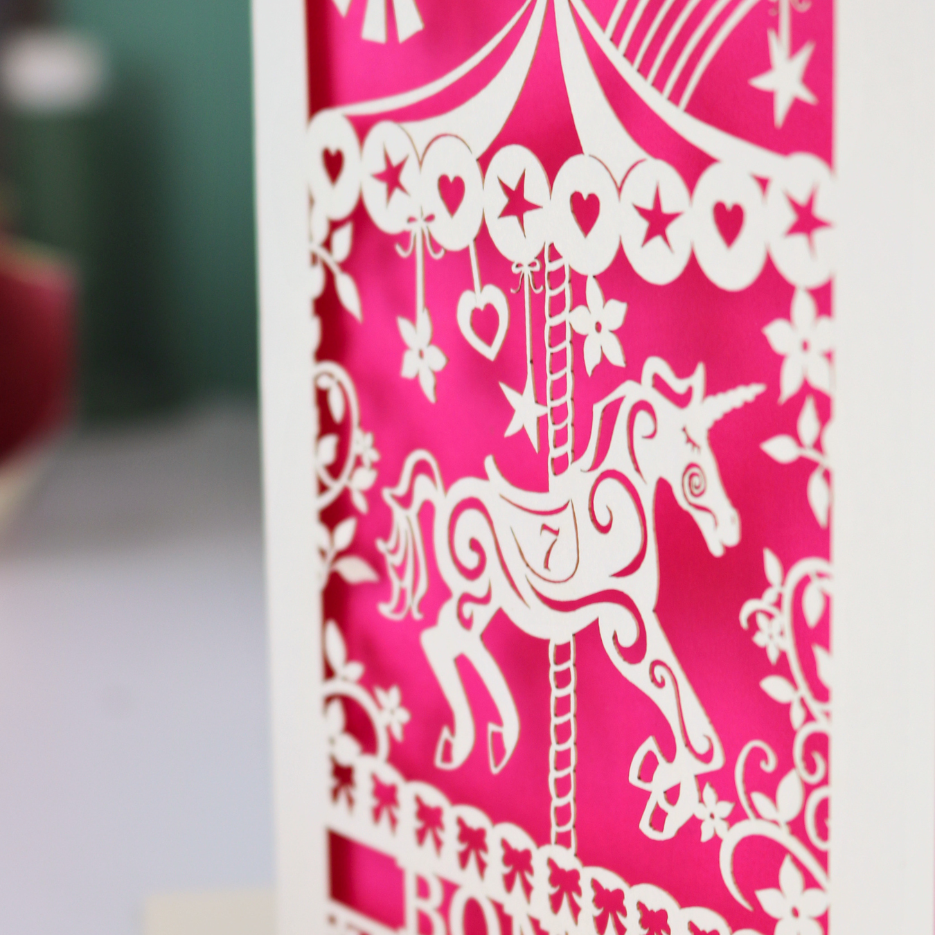 Close up detail of a laser cut girls' birthday card with unicorn carousel and flowers